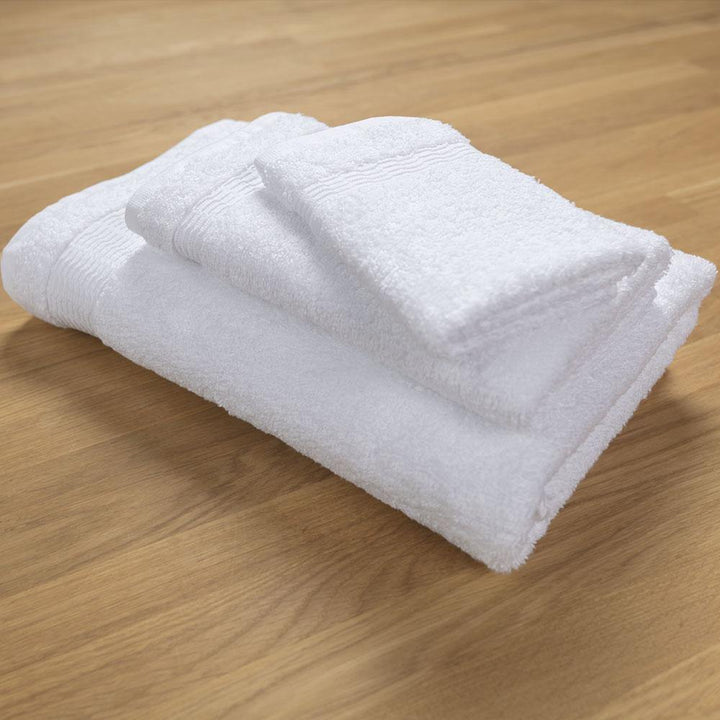 Bath towel, hand towel, and washcloth stacked on wood table